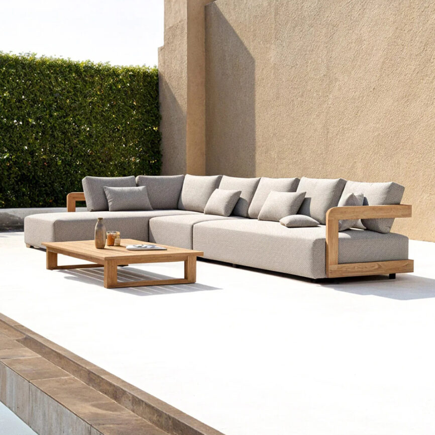 Maze corner outdoor sofa set with Grade-A teak frame, white outdoor fabric cushions, and matching coffee table on a modern patio.