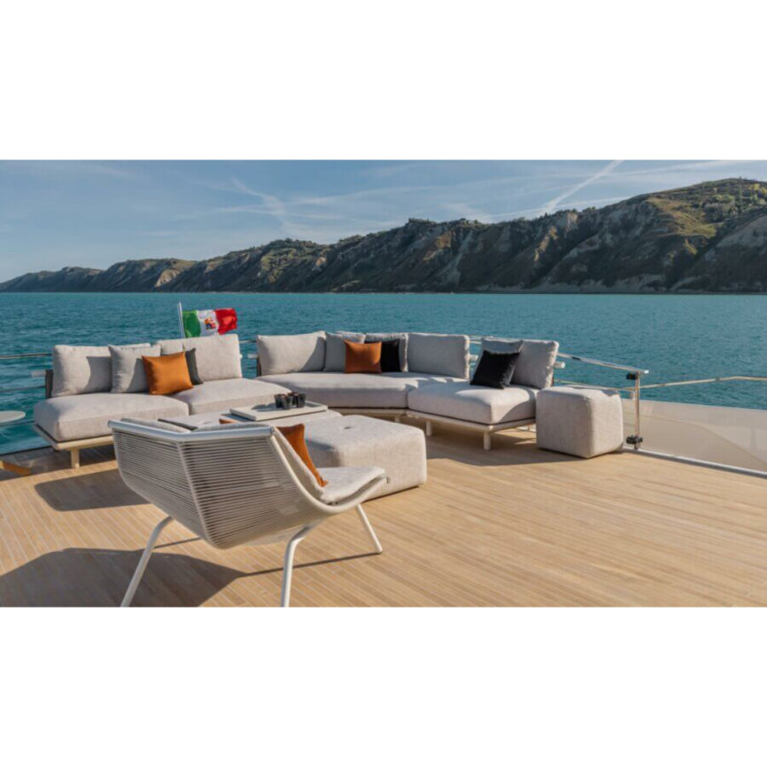 A luxurious modular outdoor lounge set placed on a yacht, featuring an L-shaped sofa, ottoman, and lounge chair, with stunning ocean and mountain views in the background.