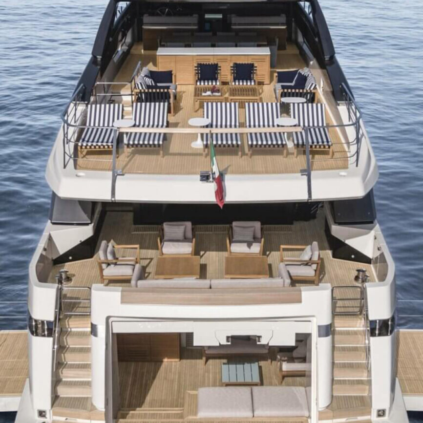 Marine-grade luxury outdoor sofa and armchair set installed on a yacht deck, featuring striped cushions and wooden frames